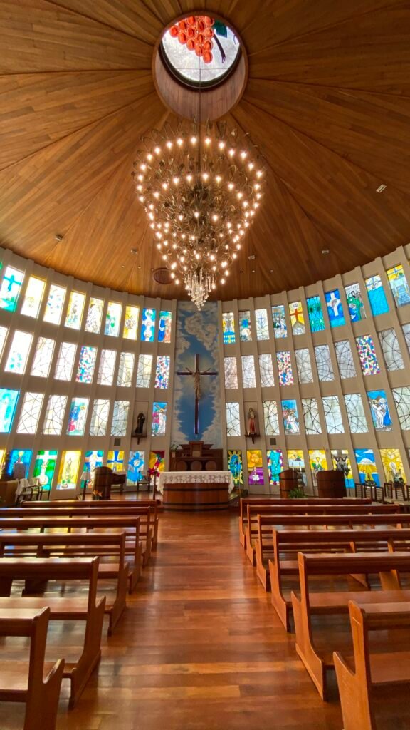 Interior da Igreja São Bento, com teto de madeira e vitrais coloridos, em Bento Gonçalves (RS)