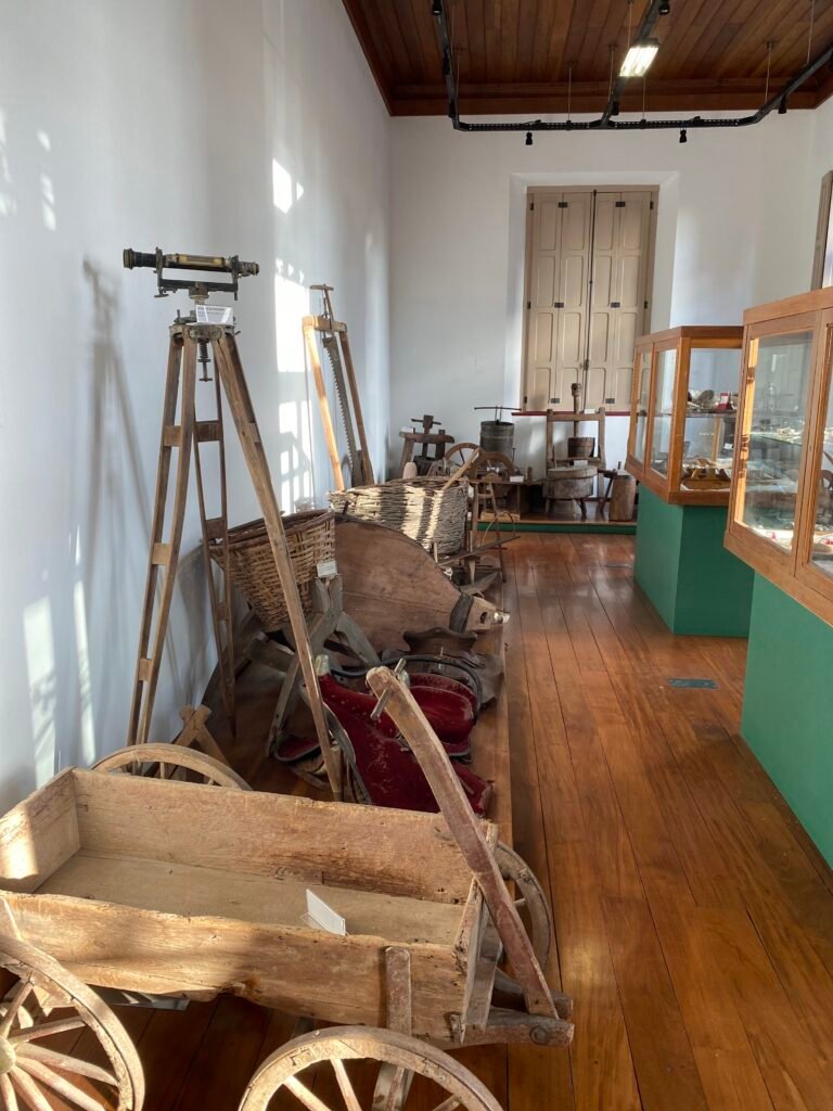 Carroça de madeira e vitrines em sala do Museu do Imigrante, em Bento Gonçalves (RS)