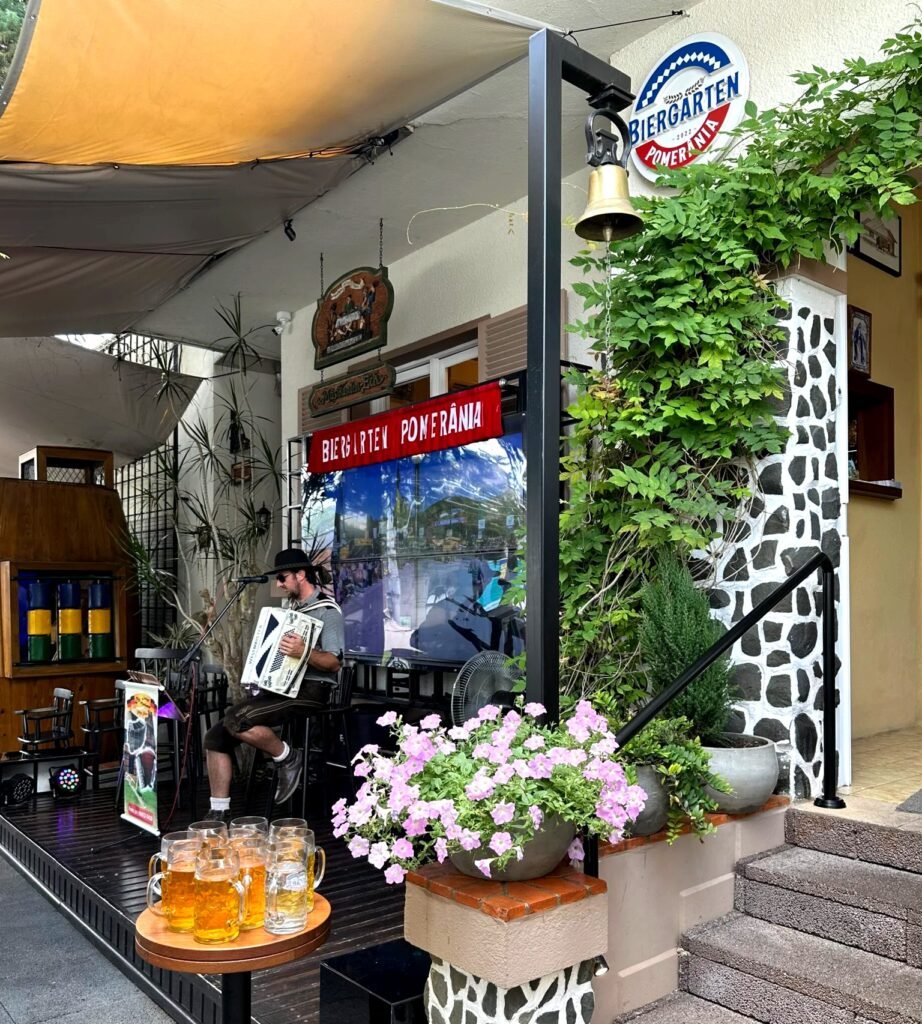 Entrada do Biergarten Pomerânia, com acordeonista e canecas de chope, em Pomerode (SC)